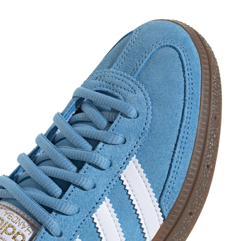 Youth light blue suede sneaker close-up with blue laces, white stripes, and gum edge