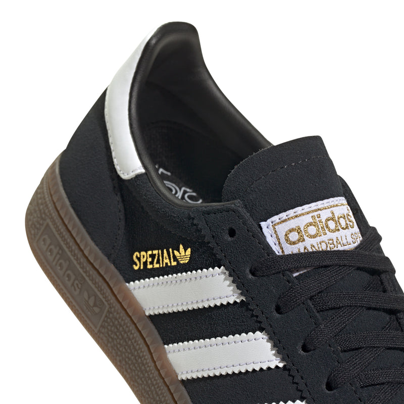 Youth black adidas sneakers with Spezial tongue patch, white stripes, and laces