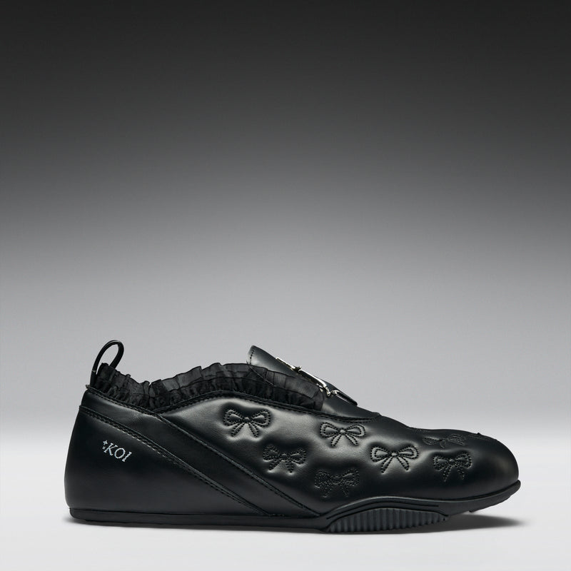 Black sneaker with bow designs on a gray background