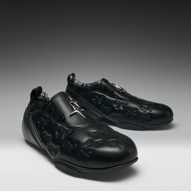 Pair of black shoes with floral embroidery on a gray background