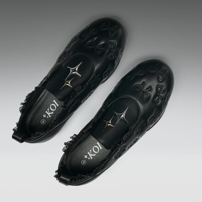 Pair of black loafers with intricate designs and 'Koi' branding on a gray background