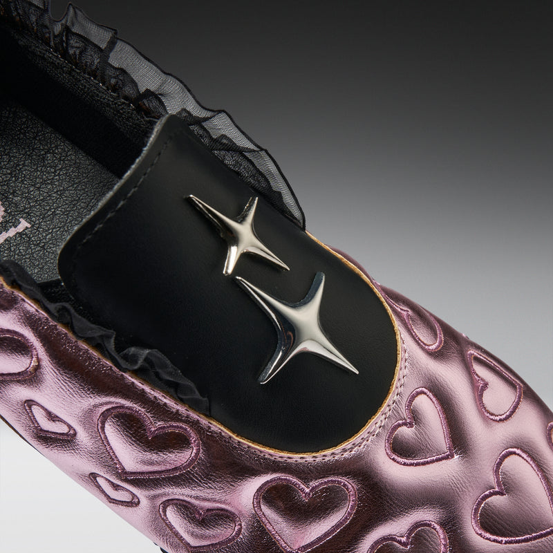 Close-up of a shoe with heart patterns and a metallic buckle on a gradient background
