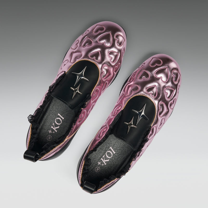Pair of purple heart-patterned shoes with black soles on a gray background
