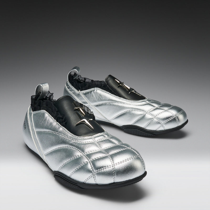 Pair of silver shoes with black accents on a gray background