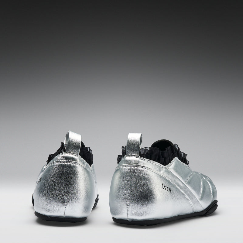 Pair of silver athletic shoes with black soles on a gray background