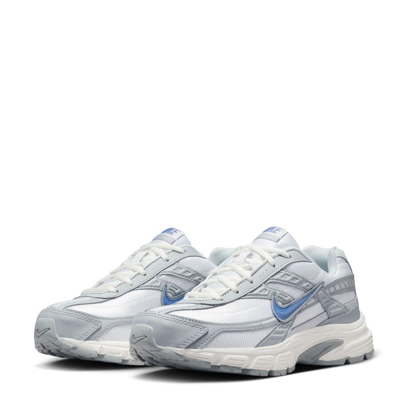 Pair of women’s white running shoes with gray accents and blue Swoosh, lace-up style.