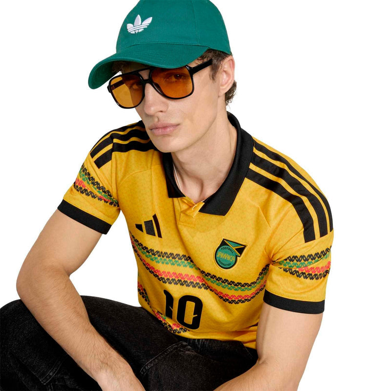 Men's yellow soccer polo with black collar stripes, crest logo, and sunglasses