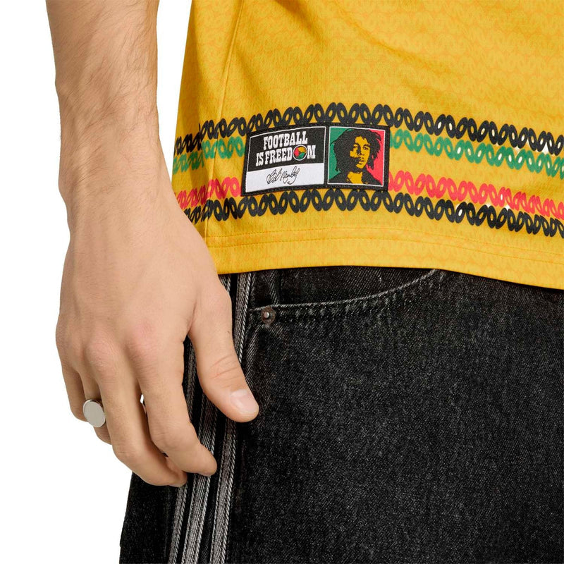 Close-up of yellow soccer jersey hem with multicolor stripe pattern and tag
