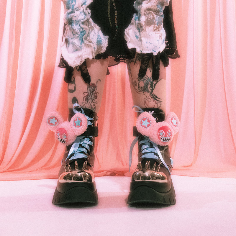 Jazmin Bean wearing black boots with pink decorative elements against a pink curtain background