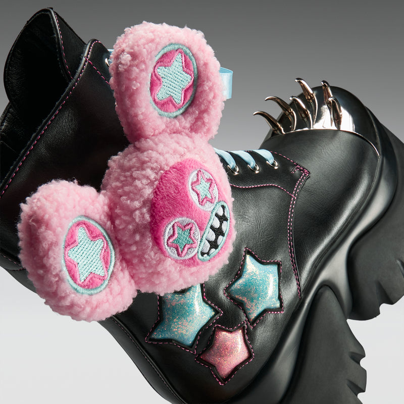 Black boot with pink fuzzy patches and star designs on a gray background
