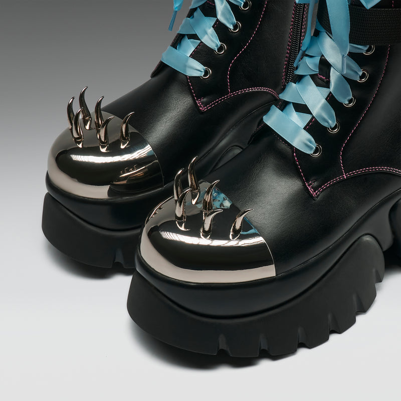Black boots with metallic spikes and blue laces on a gradient background