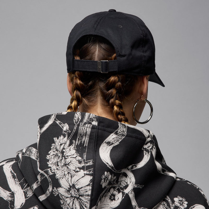 Black cap back view with adjustable strap, worn on model