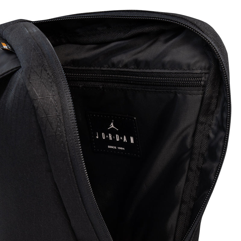 Black crossbody bag interior view with zippered pocket and Jordan label patch.