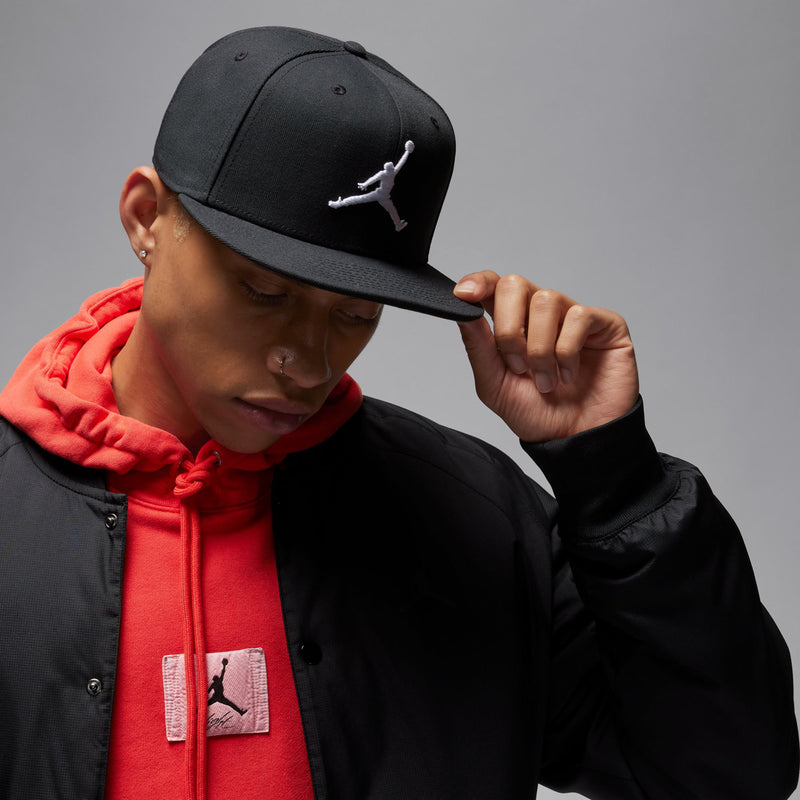 Black snapback cap with white Jumpman logo, worn and adjusted by hand