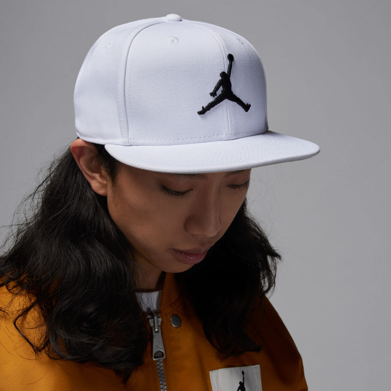 White snapback cap with black Jumpman logo, worn in profile by a model