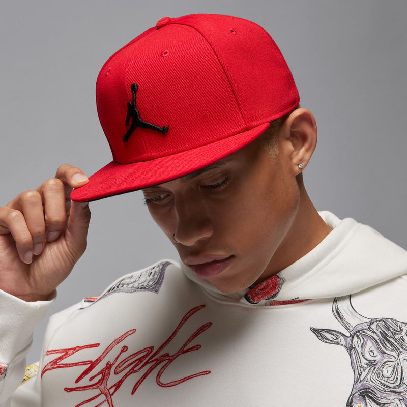 Red snapback cap worn with black Jumpman logo and curved brim