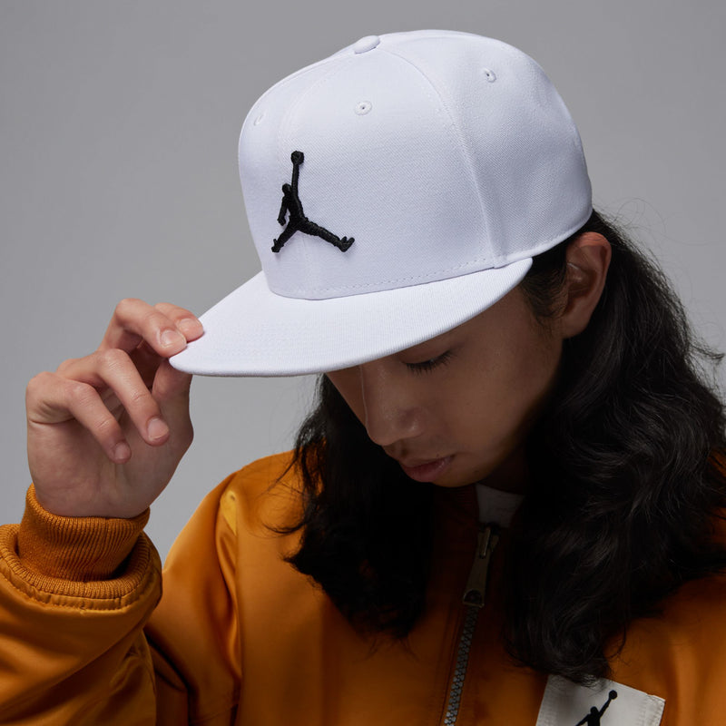 White snapback cap with black Jumpman logo, model holding the brim