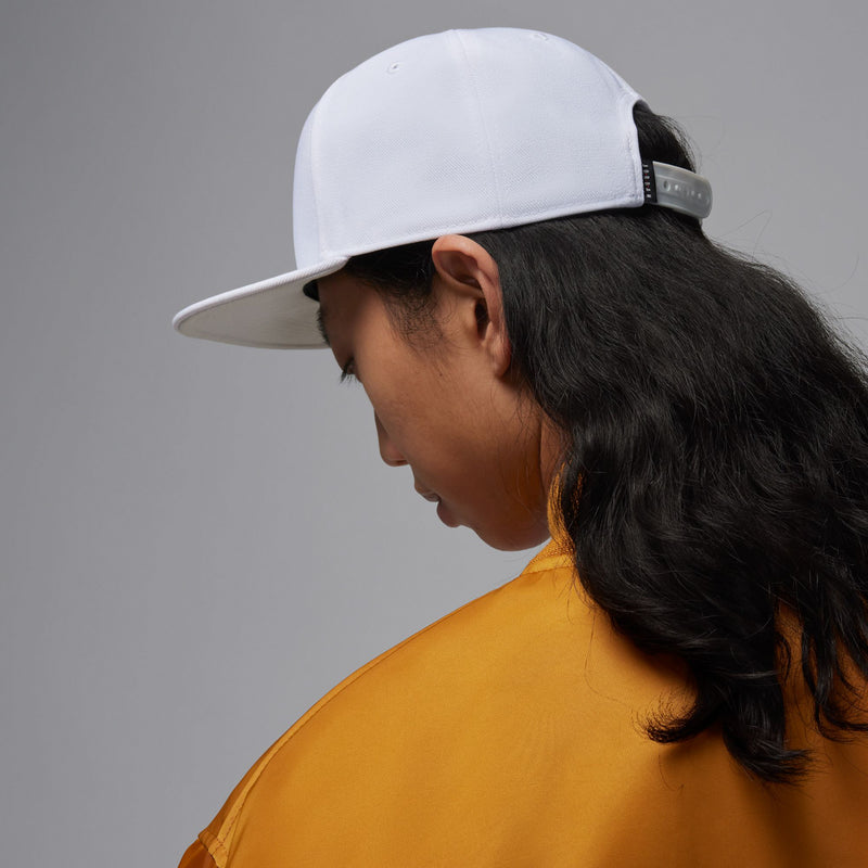 White snapback cap side profile with black Jumpman logo and adjustable strap