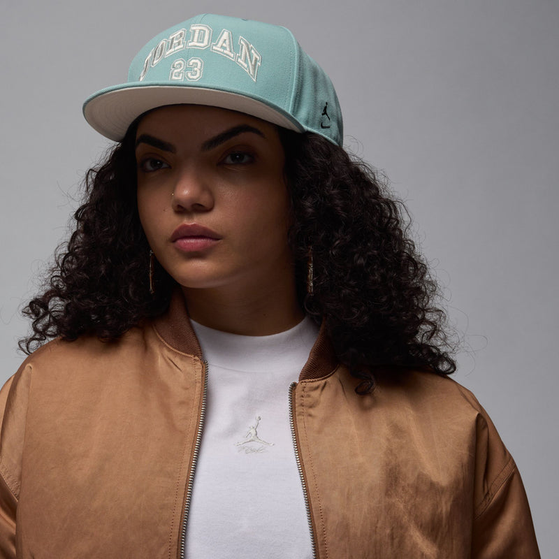 Light teal snapback cap with arched 'JORDAN' text, '23' patch, and flat bill