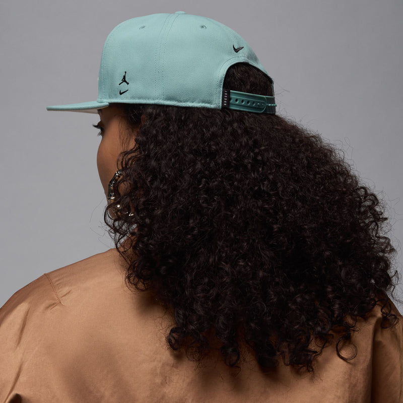 Light teal snapback cap with small logo accents and adjustable rear strap, flat bill