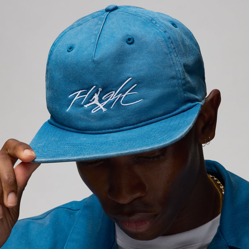 Faded blue strapback cap worn forward with “Flight” logo on the crown