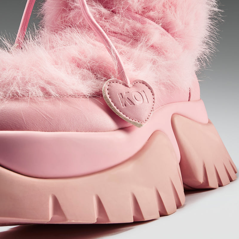 Pink fuzzy shoe with a heart-shaped logo on a gray background