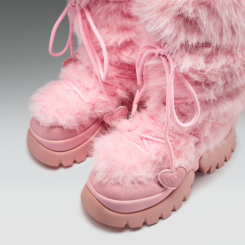 Pink fuzzy boots with a fluffy texture on a light gray background