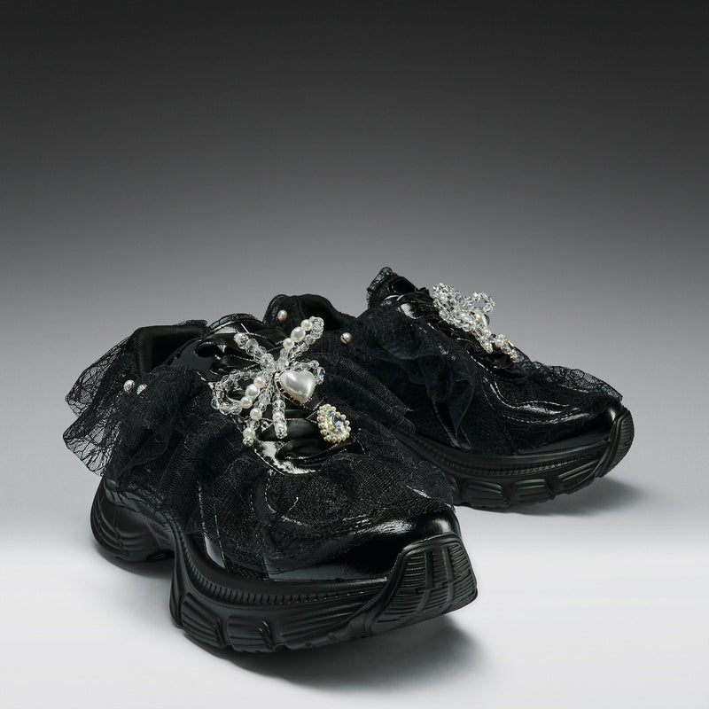 Black sneakers with decorative elements on a gradient background