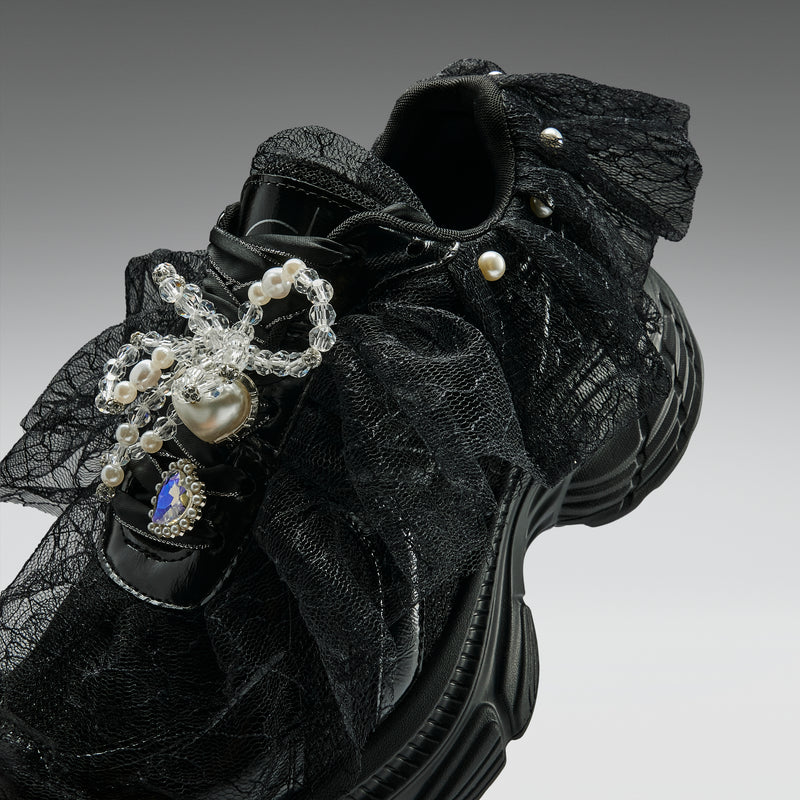 Black lace shoe with decorative elements on a gray background