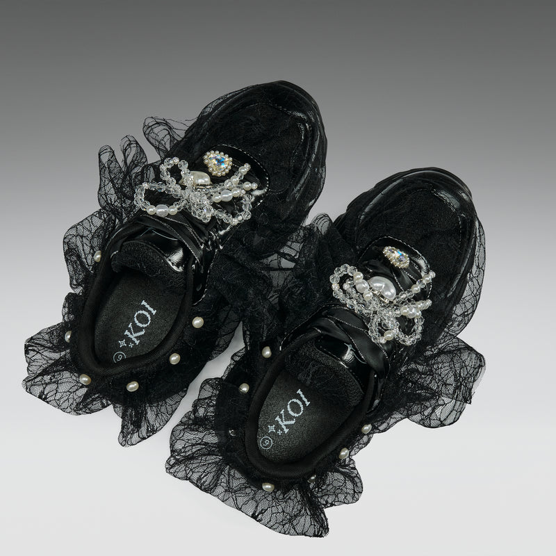 Black sneakers with lace and embellishments on a gradient background