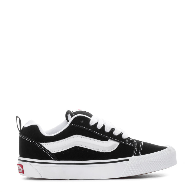 Black and white low-top sneakers with white stripe detailing and lace-up front