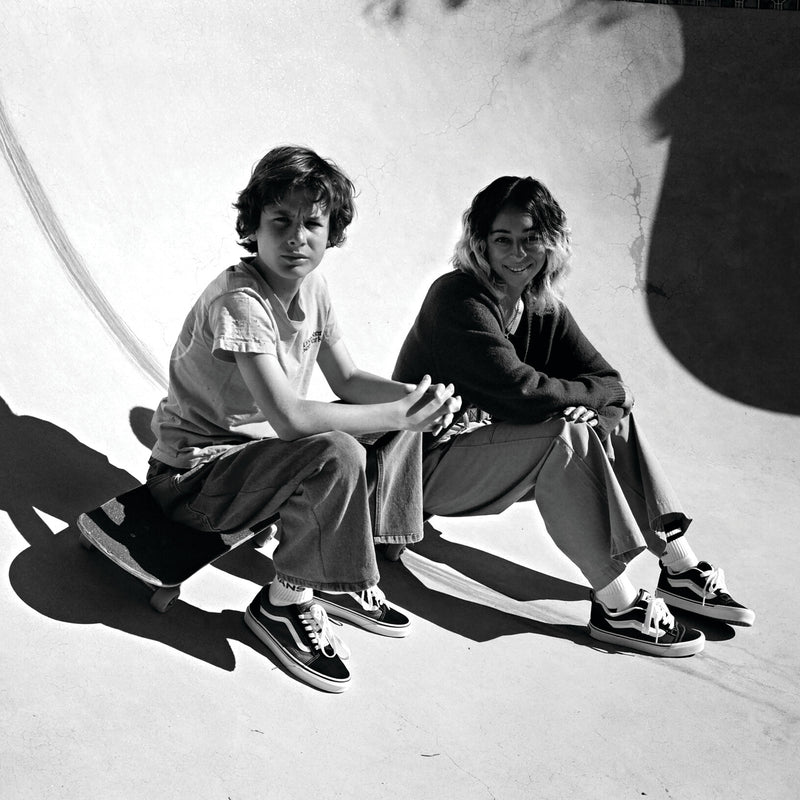 Pair of black and white low-top sneakers worn on feet, lace-up with white stripes
