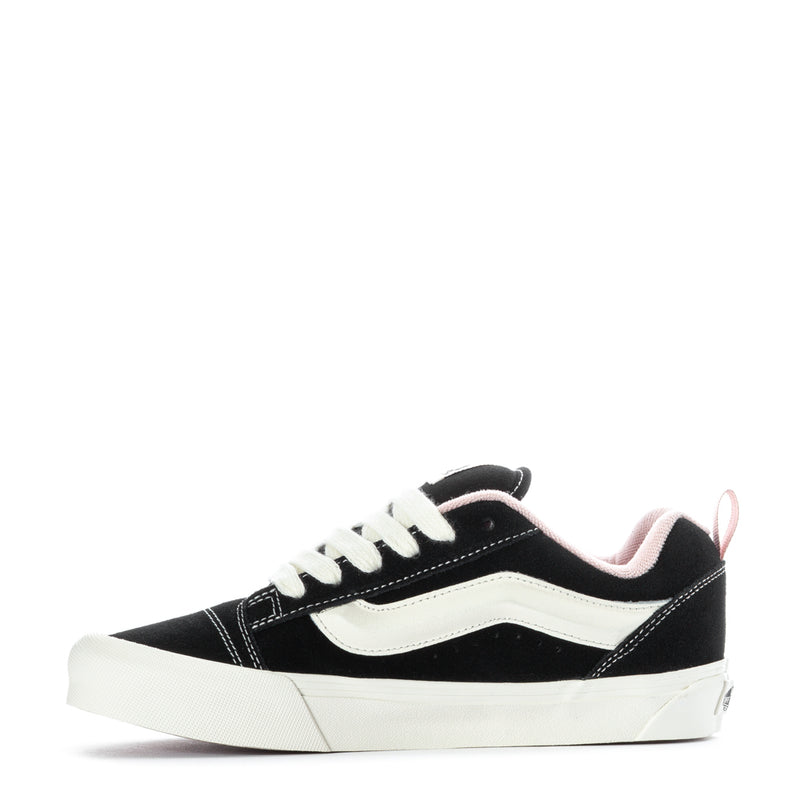 Black and white low-top sneakers with pink collar lining, front quarter view.