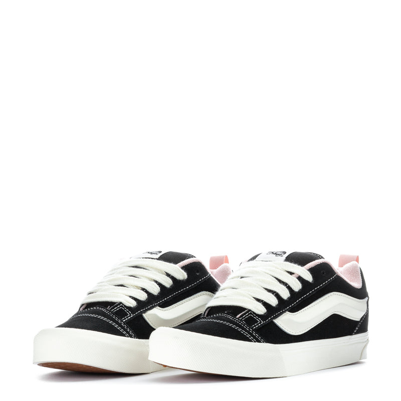 Pair of black low-top sneakers with white wavy stripe and white laces.