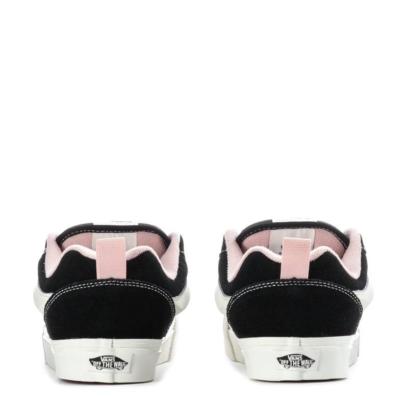 Black low-top sneakers with white rubber sole and pink heel lining, back view.