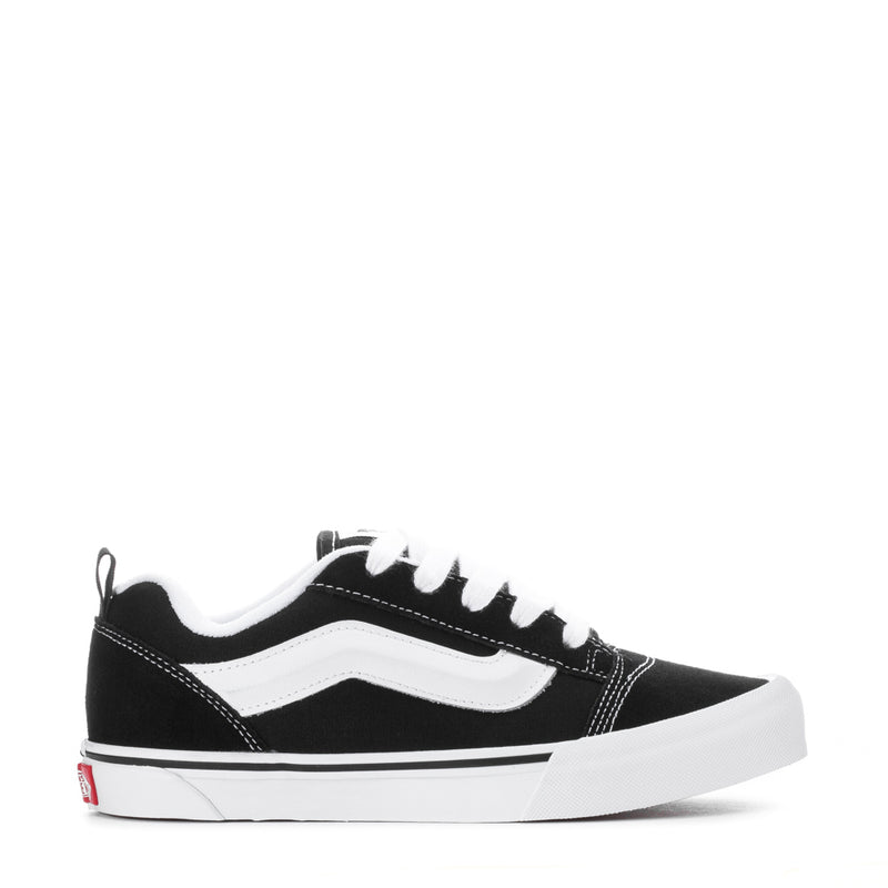 Black and white youth lace-up sneakers with wavy side stripe and white midsole.