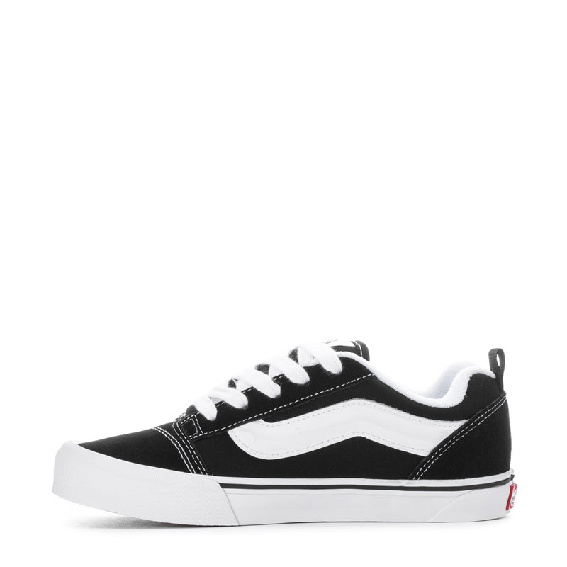 Black youth lace-up sneakers with white wavy side panel and chunky white sole.