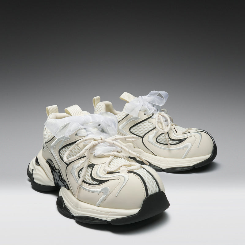 White sneakers with black soles on a gradient gray background
