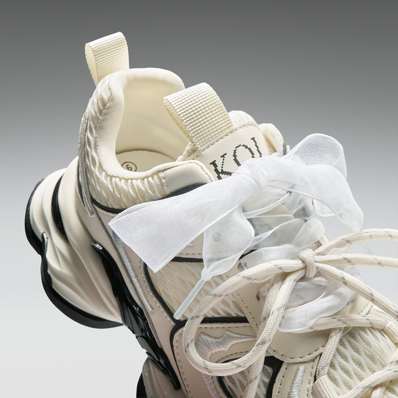 Close-up of a beige sneaker with white laces on a gray background