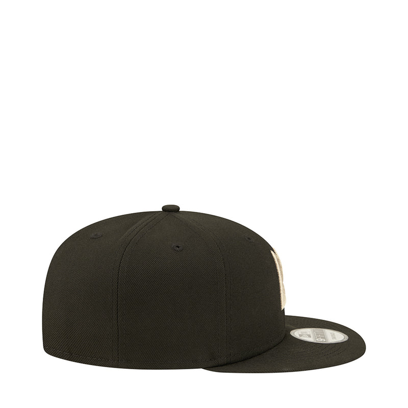 Dark baseball cap with flat brim and side patch; front logo not visible