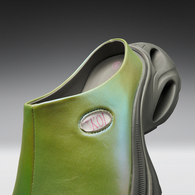 Green slip-on shoe with a brand logo on a gray background