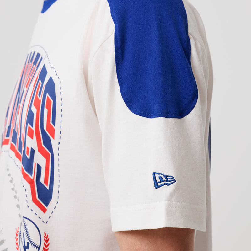 White baseball tee sleeve with blue raglan panel and small New Era logo patch