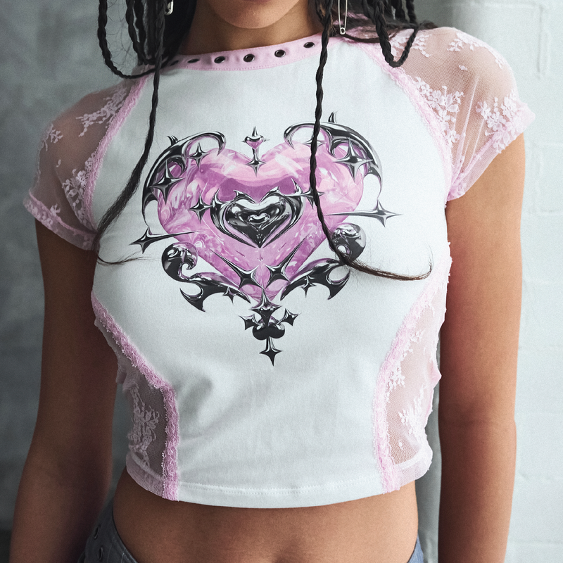 White crop top with pink lace details and a heart design on a plain background