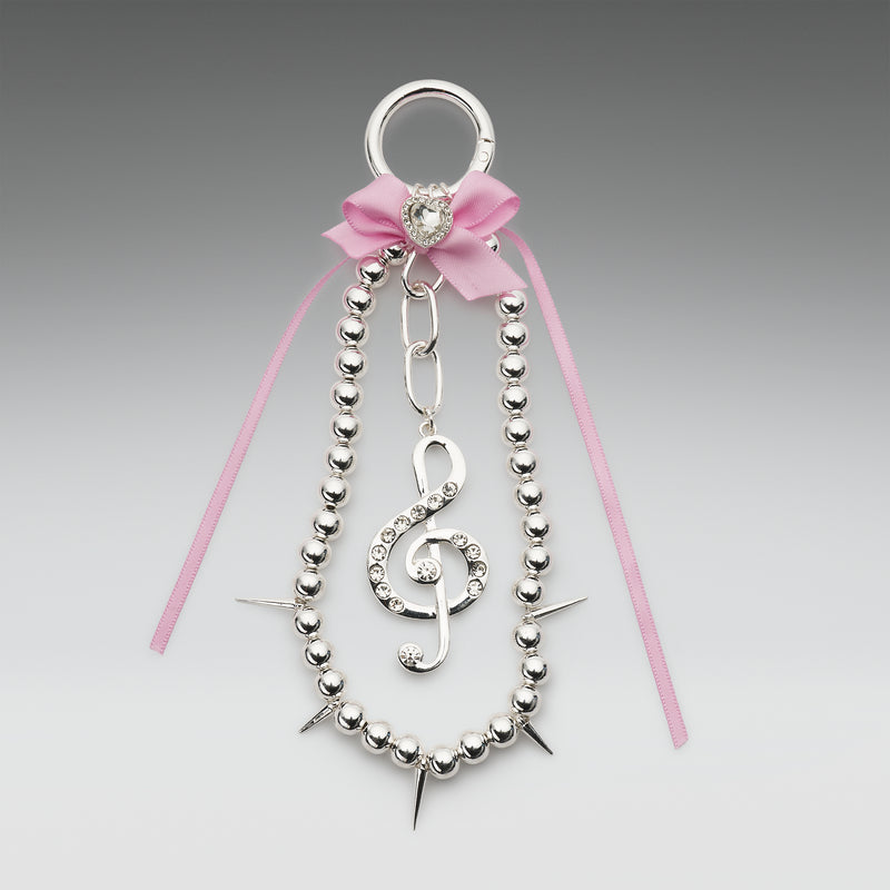 Decorative hair clip with silver beads, pink ribbon, and treble clef design on a gray background