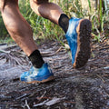 Person trail running outdoors wearing blue GORUCK rucking shoes on rugged terrain