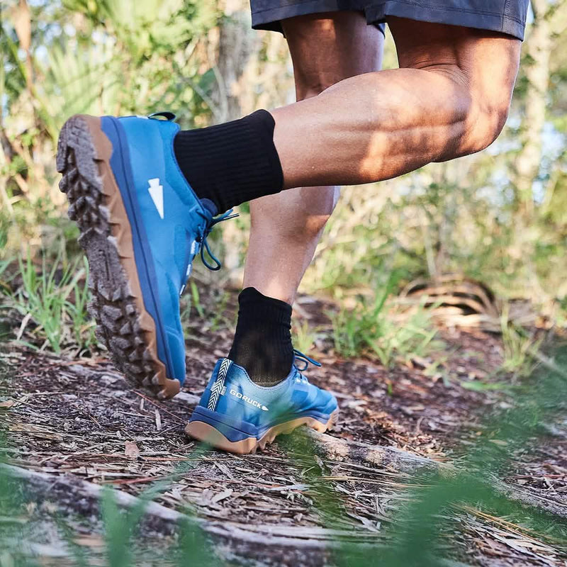 Person hiking outdoors wearing blue GORUCK rucking shoes on a forest trail