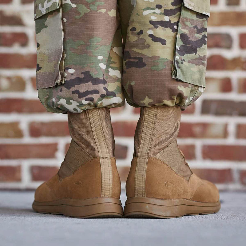 GORUCK military boots with bloused camouflage pants, outdoor brick wall background