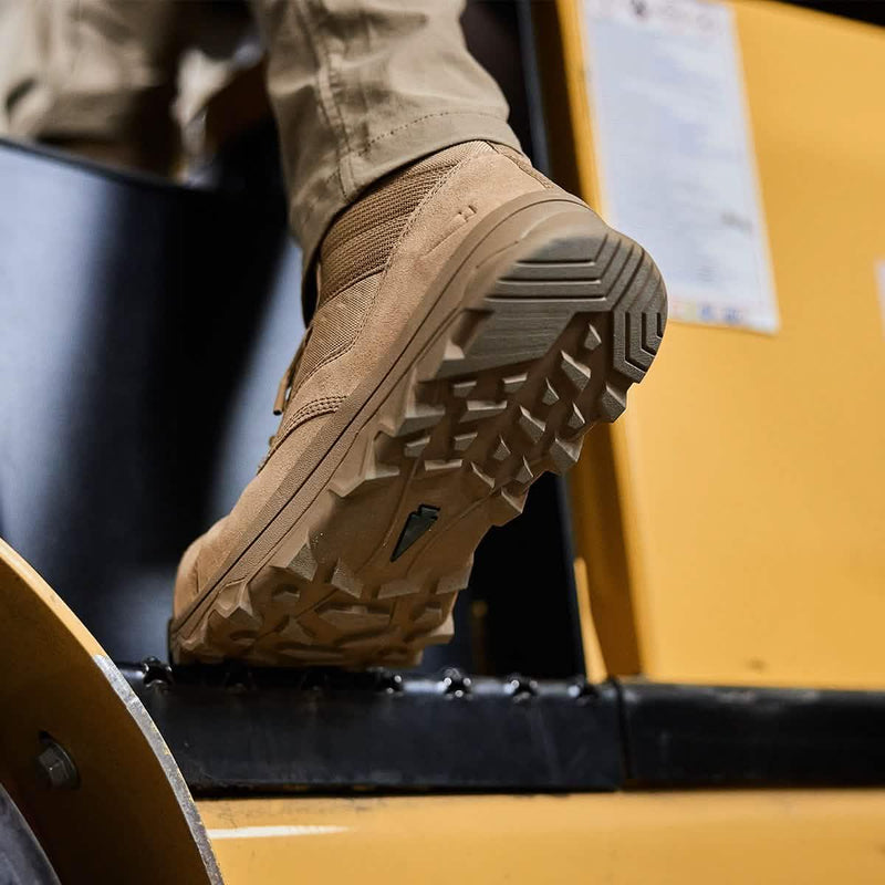 GORUCK tan rucking boot with rugged tread on a yellow industrial step