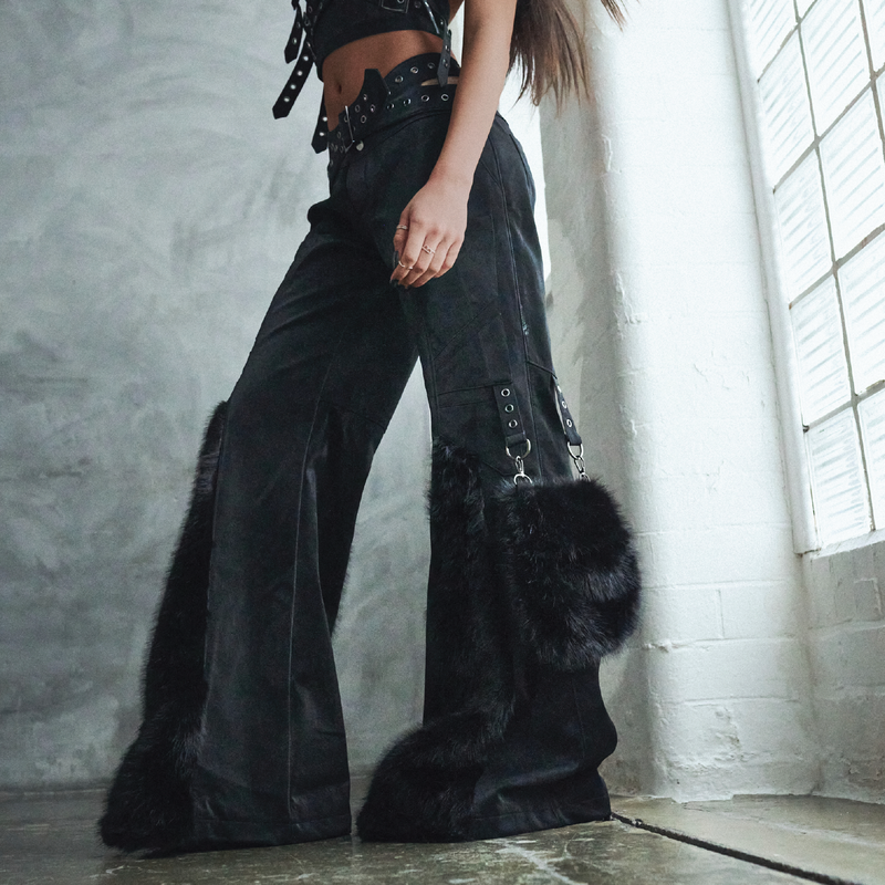 Person wearing black wide-leg pants with fur details in a room with a window.