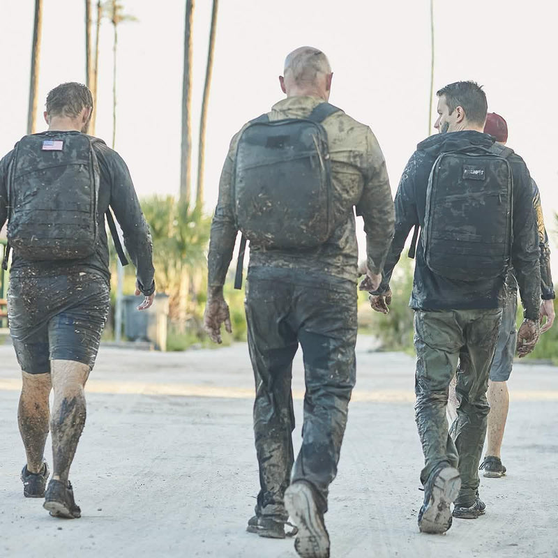 Group of people in muddy clothes wearing GORUCK backpacks during outdoor rucking event